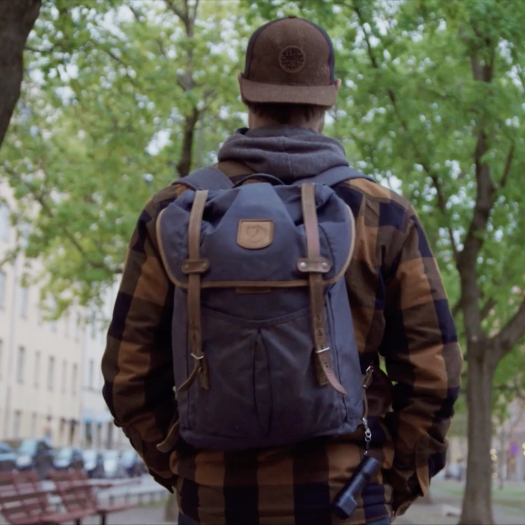 Image of a black Plegium Combo defence spray attached to a backpack